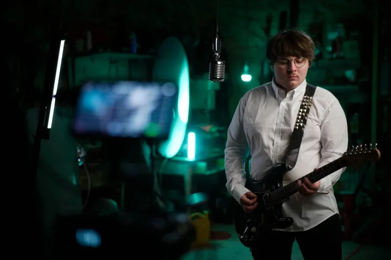 Hudebník s kytarou v nasvíceném ateliéru