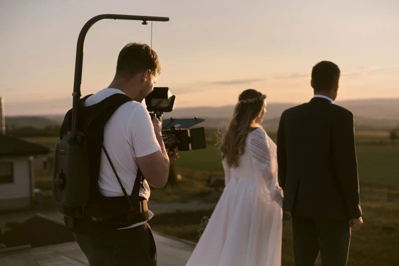 Kameraman natáčí novomanžele při západu slunce
